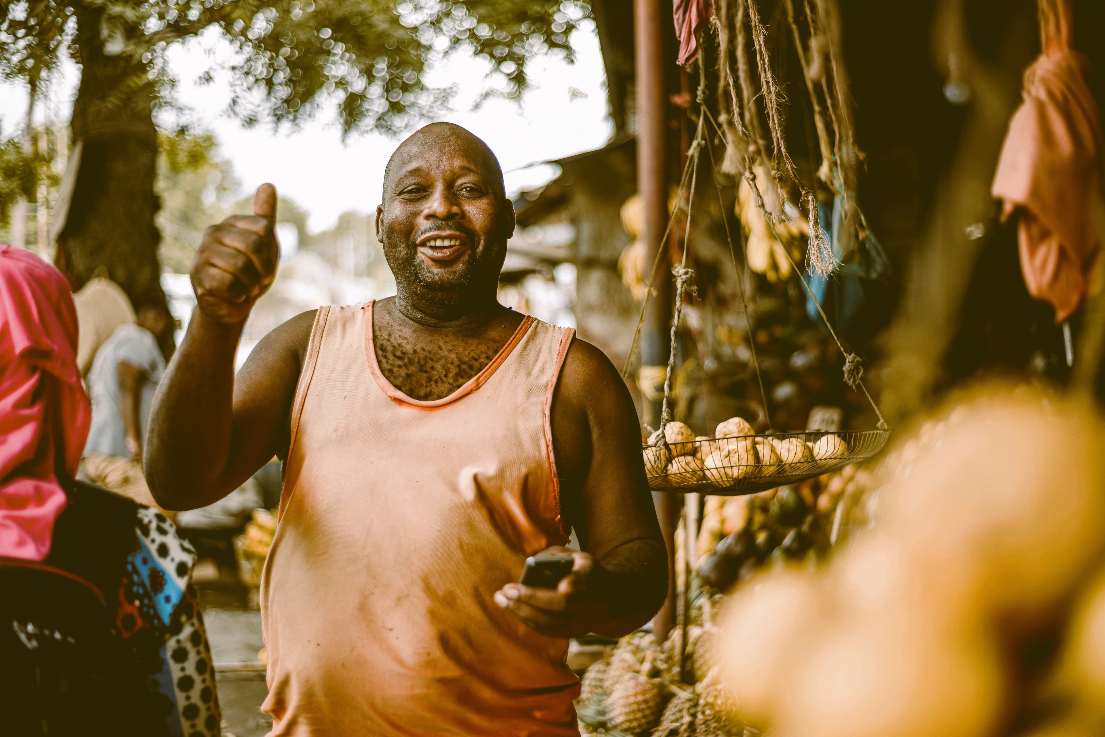 A fruit seller giving a thumbs up at his shop
